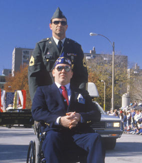two veterans stood on the street
one in a wheelchair